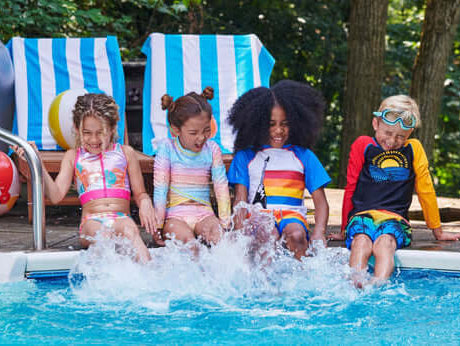 Four stylish kids splashing in a pool, showcasing fun summer swimwear and vibrant beach vibes.
