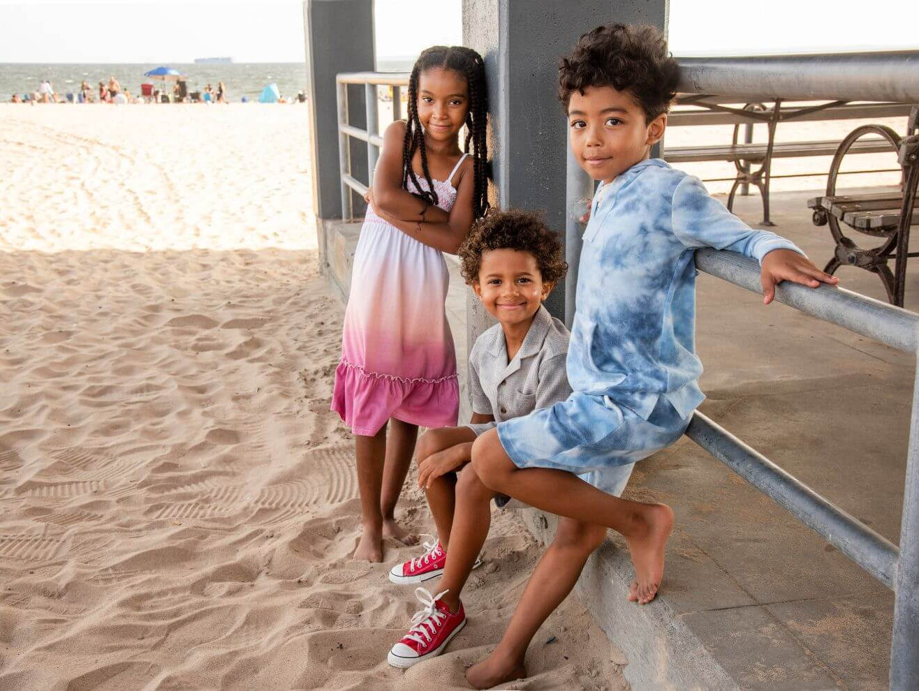 Three stylish kids at the beach in playful outfits, showcasing Appaman's trendy summer fashion for boys and girls.