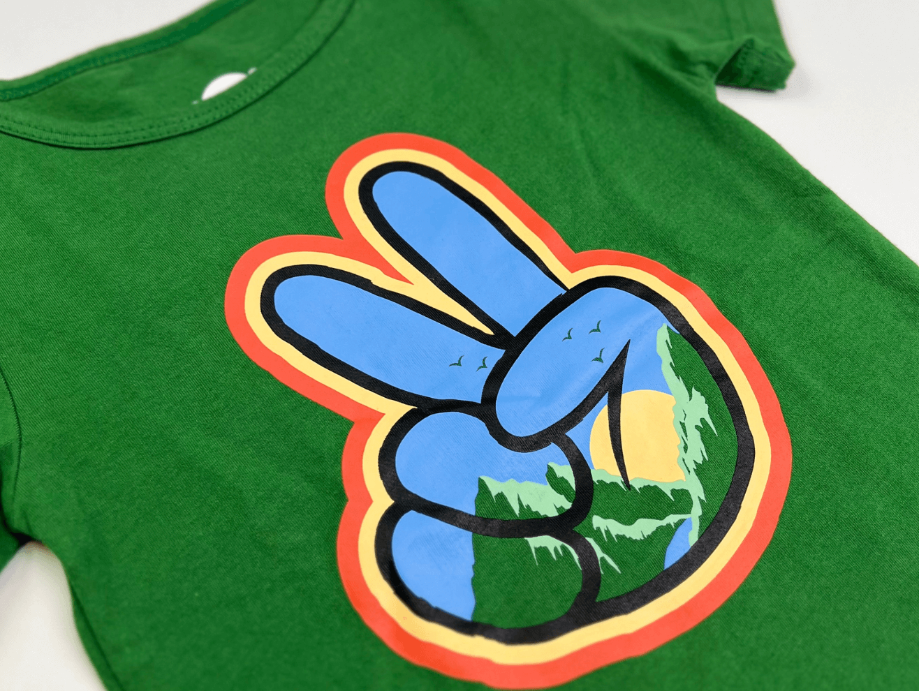 Green kids' t-shirt featuring a peace sign design with nature imagery for Earth Day celebrations.