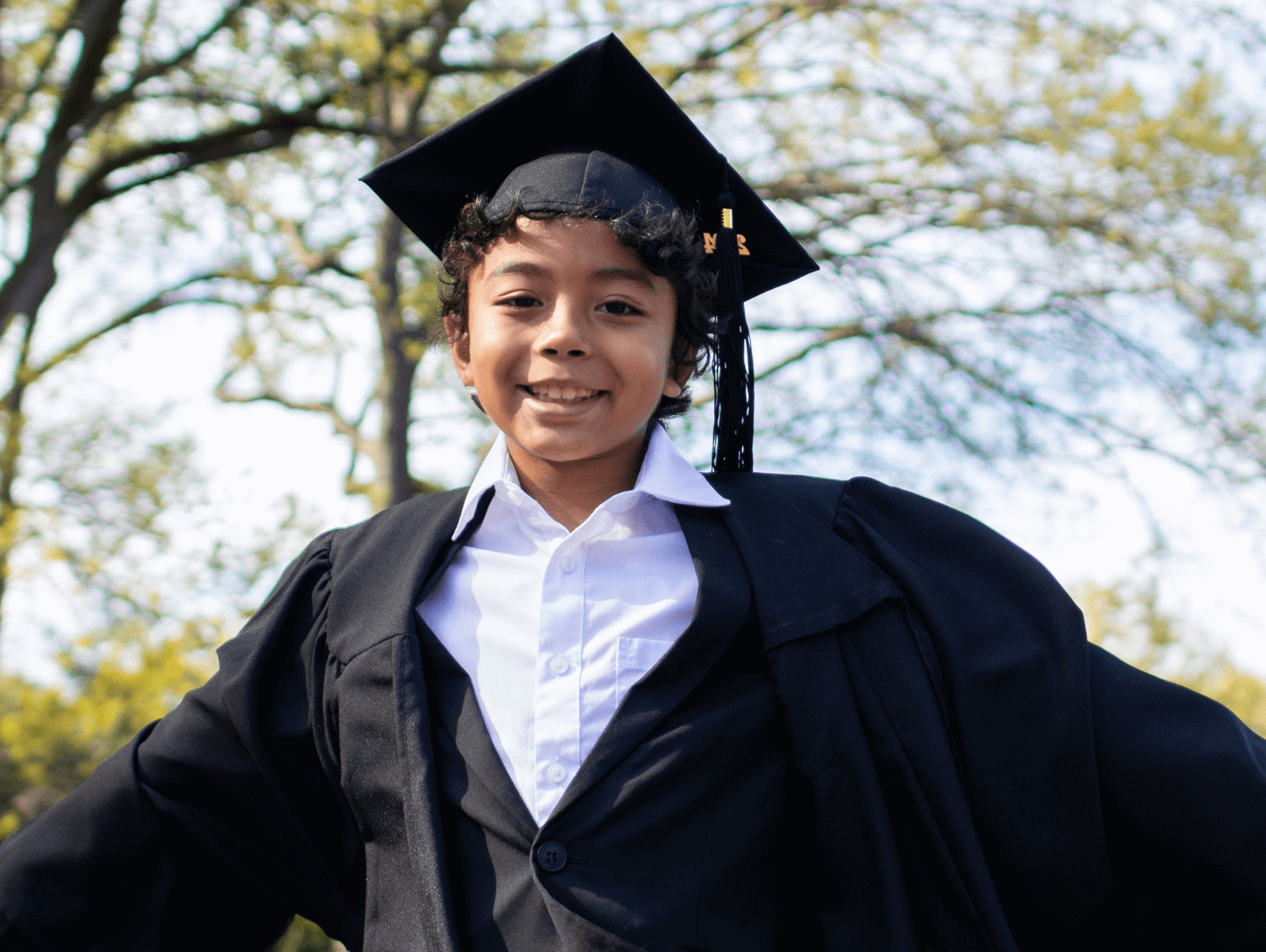 Celebrating preschool graduation: A joyful boy in cap and gown, ready to take on new adventures in style.