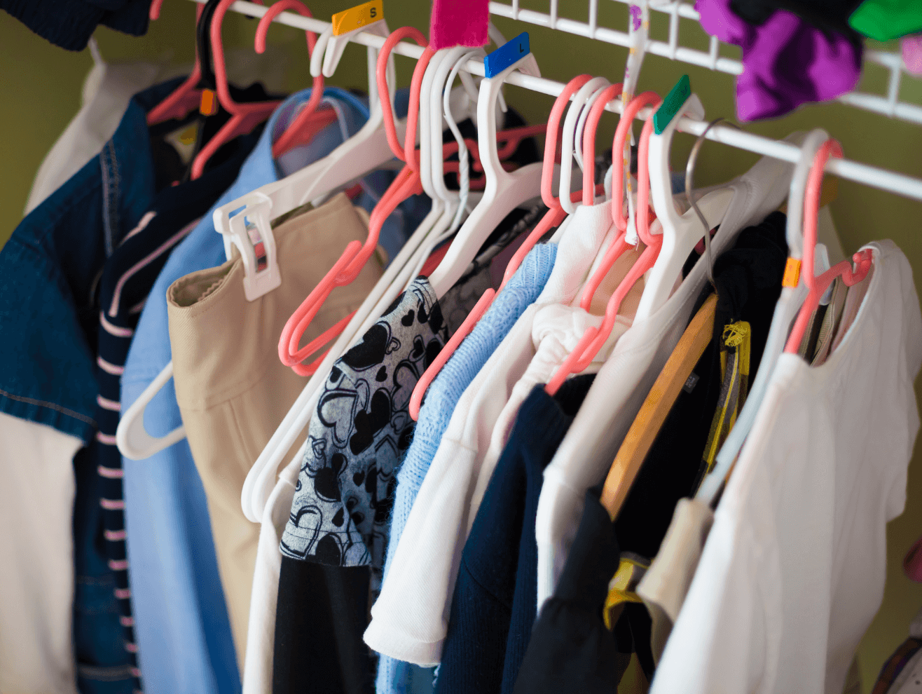 A colorful assortment of kids' clothes on hangers, showcasing trendy styles for boys and girls.