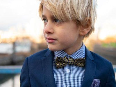 Stylish boy in a navy suit and patterned bow tie, showcasing modern kids' fashion with effortless charm.