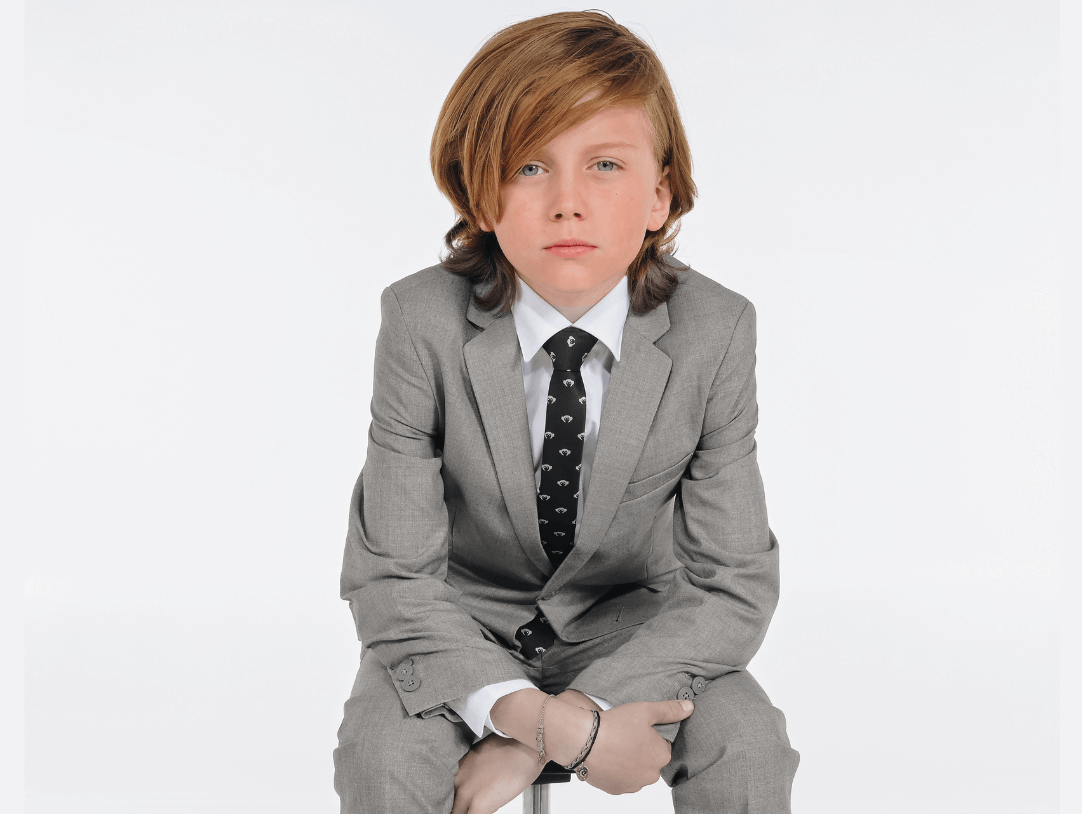 Stylish young boy in a sleek gray suit, exuding confidence with a playful vibe, perfect for dapper looks.