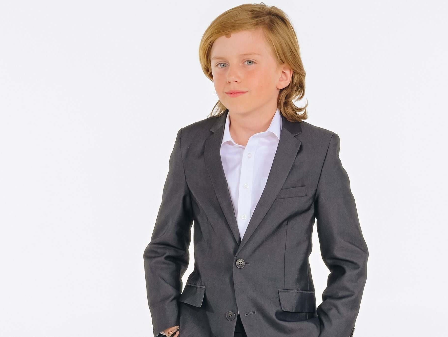 Stylish boy in a dark suit, ready for First Communion—capturing elegance and modern flair for kids' fashion.