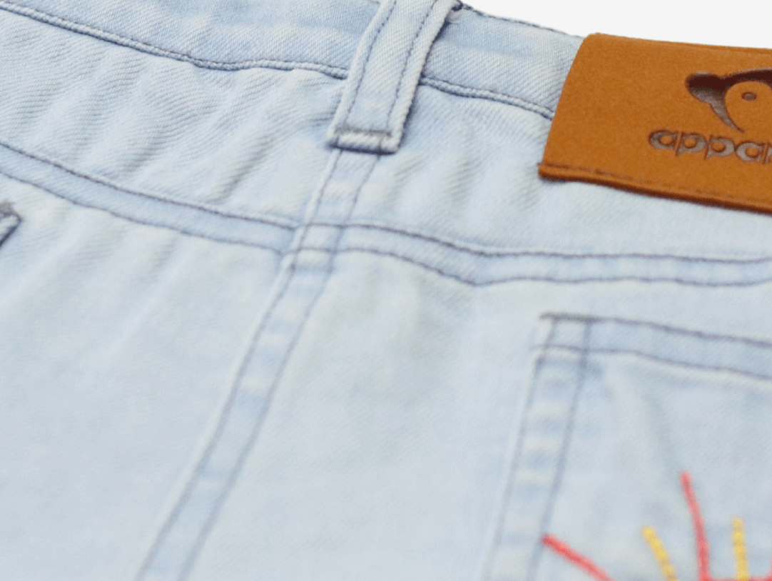 Stylish denim shorts with playful sun embroidery, perfect for trendy summer kids' outfits.