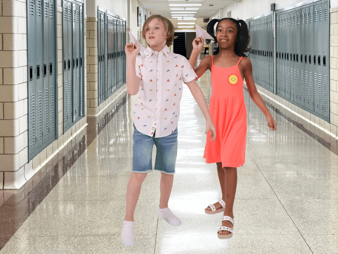 Two stylish kids celebrating the last day of school in a vibrant hallway with lockers, showcasing joyful fashion.