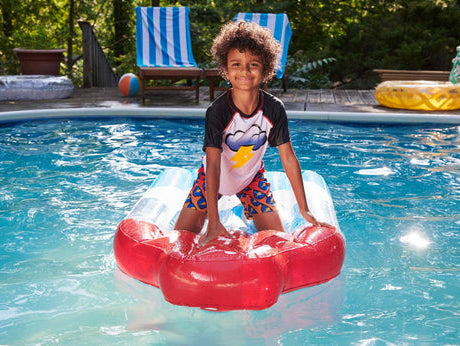 Boy in stylish swimwear having fun on a float in the pool—perfect for summer adventures and family fun!