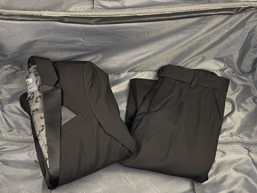 Neatly packed suit and trousers in a suitcase, showcasing stylish travel organization for kids' fashion.