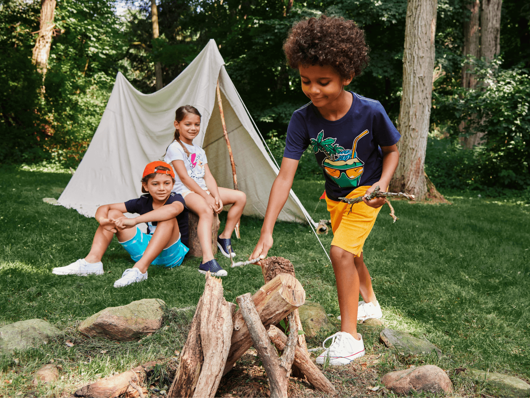 Kids having fun at summer camp, styling playful outfits by a campfire in a wooded area.