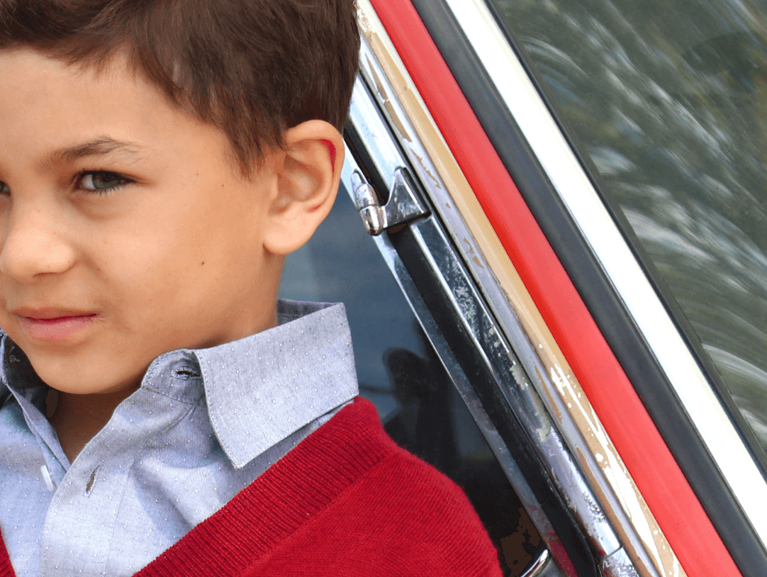 Stylish boy in a cozy red cardigan paired with a crisp shirt, embodying modern kids fashion vibes.