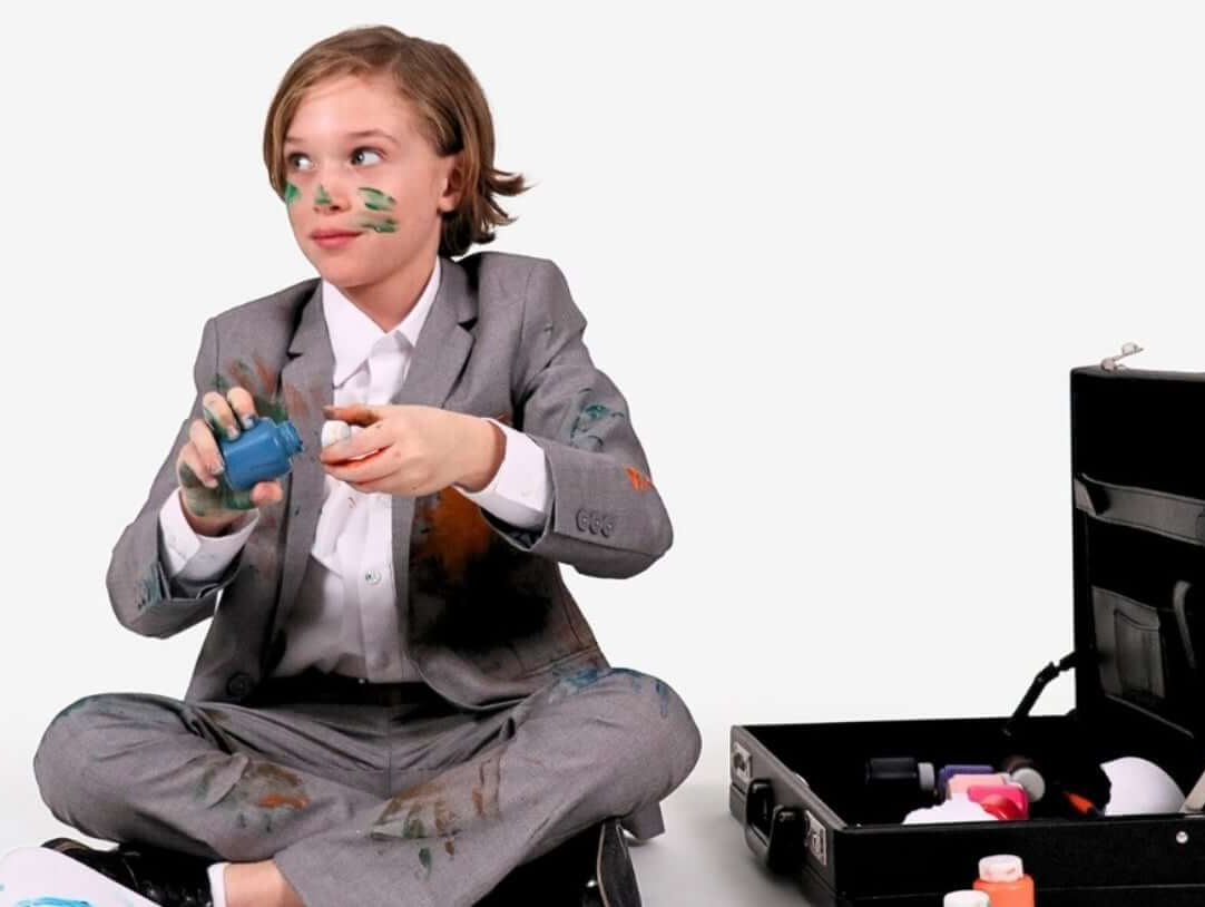 A stylish kid in a suit having fun while playing, showing that suits can be playful too!