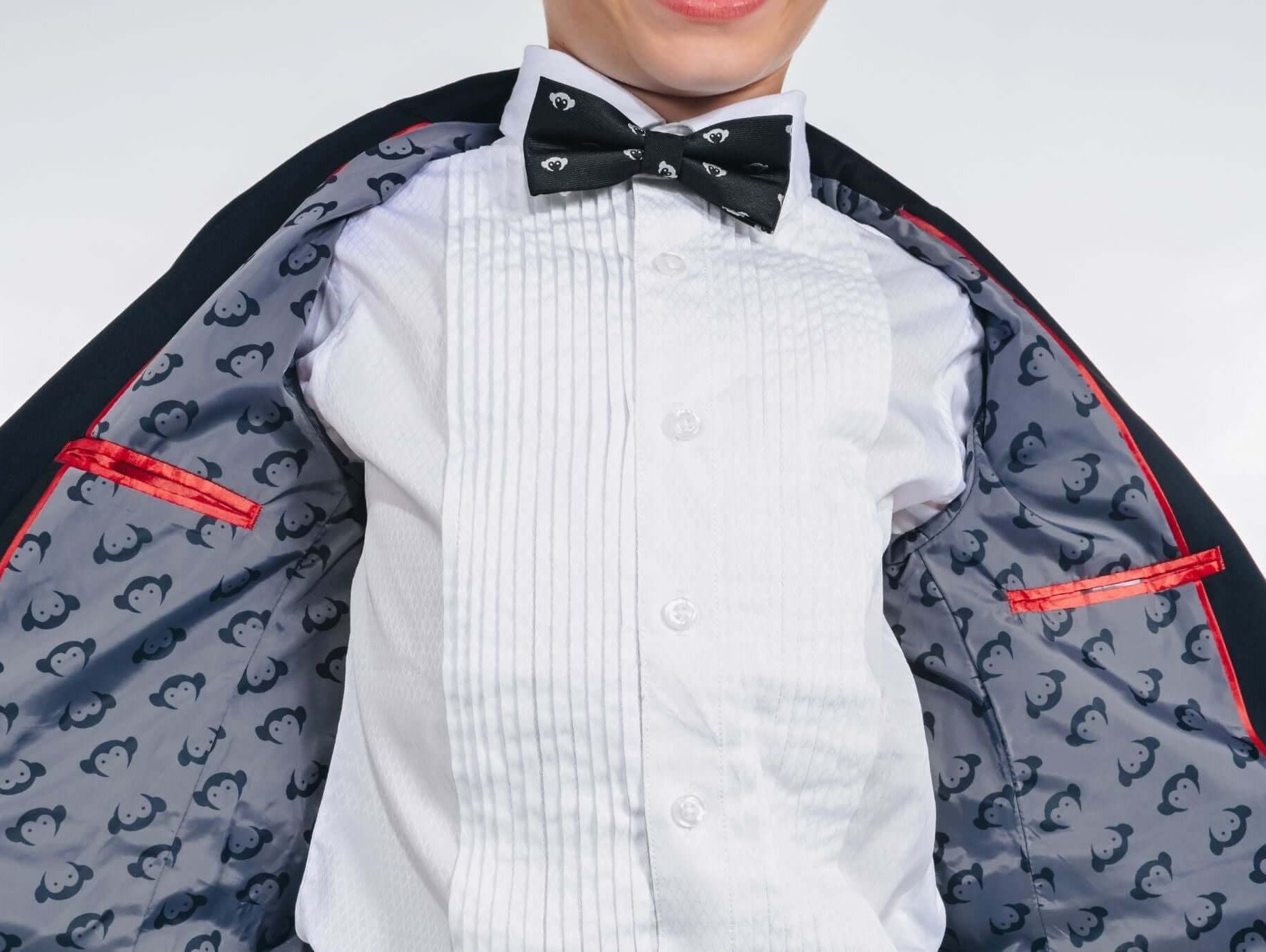 Stylish kid wearing a tuxedo with a playful penguin-lined interior, ready for a special event.
