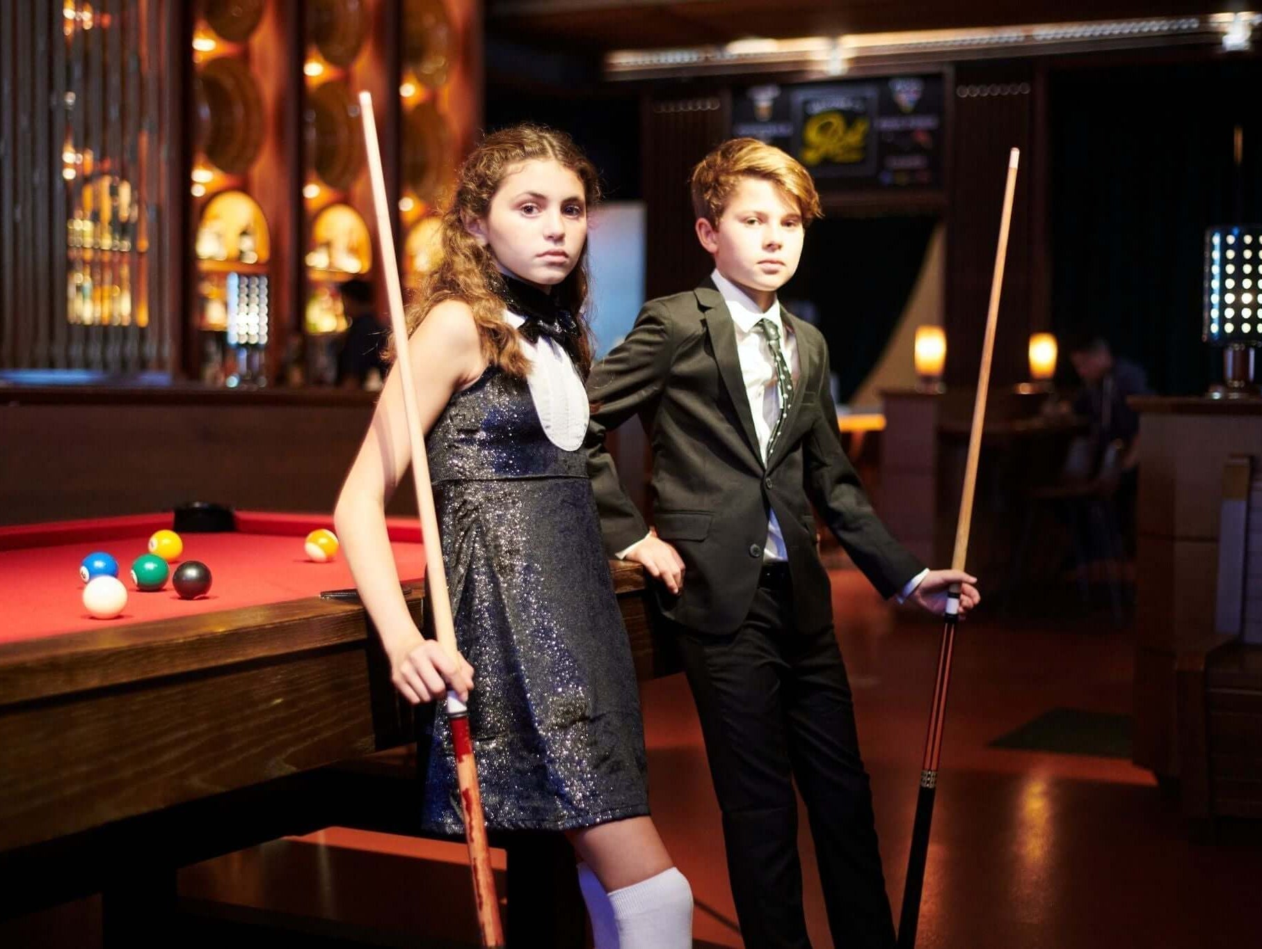 Stylish kids posing with pool cues, showcasing formal and semi-formal attire options for modern youth.