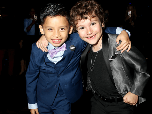 Two stylish boys in dapper suits pose playfully together, showcasing kids' fashion and fun styling tips.