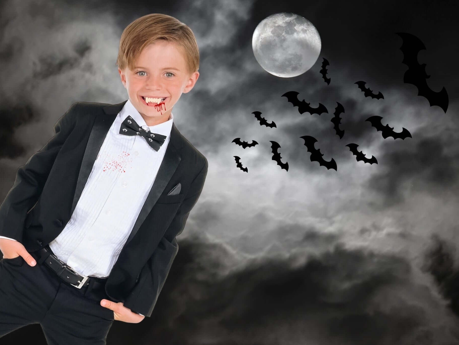 Charming boy in a classy suit with vampire-themed costume for Halloween, surrounded by bats and a full moon.