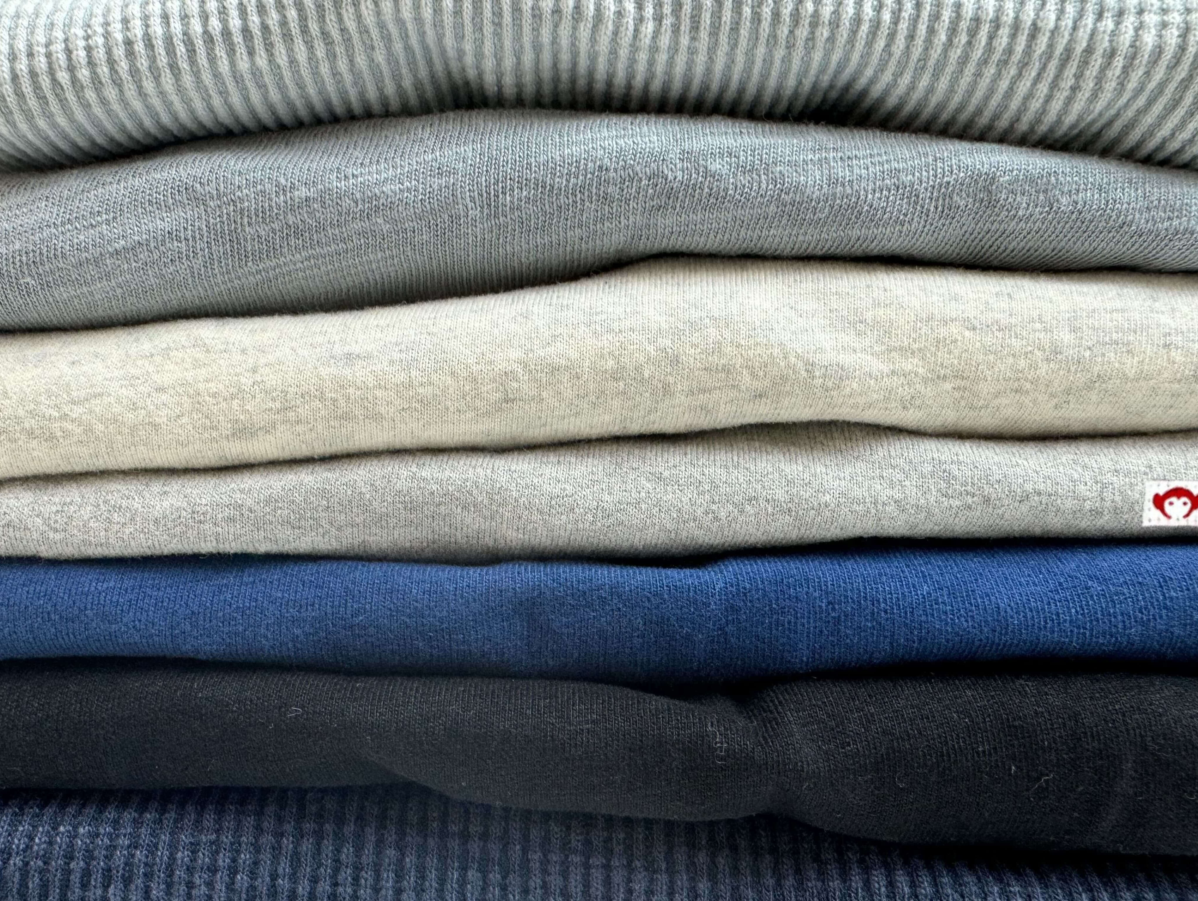 A stylish stack of soft, cozy sweaters in muted tones, perfect for dressing kids with sensitive skin.
