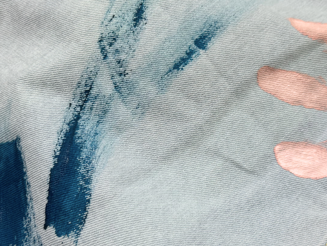 Close-up of paint-stained denim, showcasing vibrant brush strokes and playful handprints from creative kids' art projects.