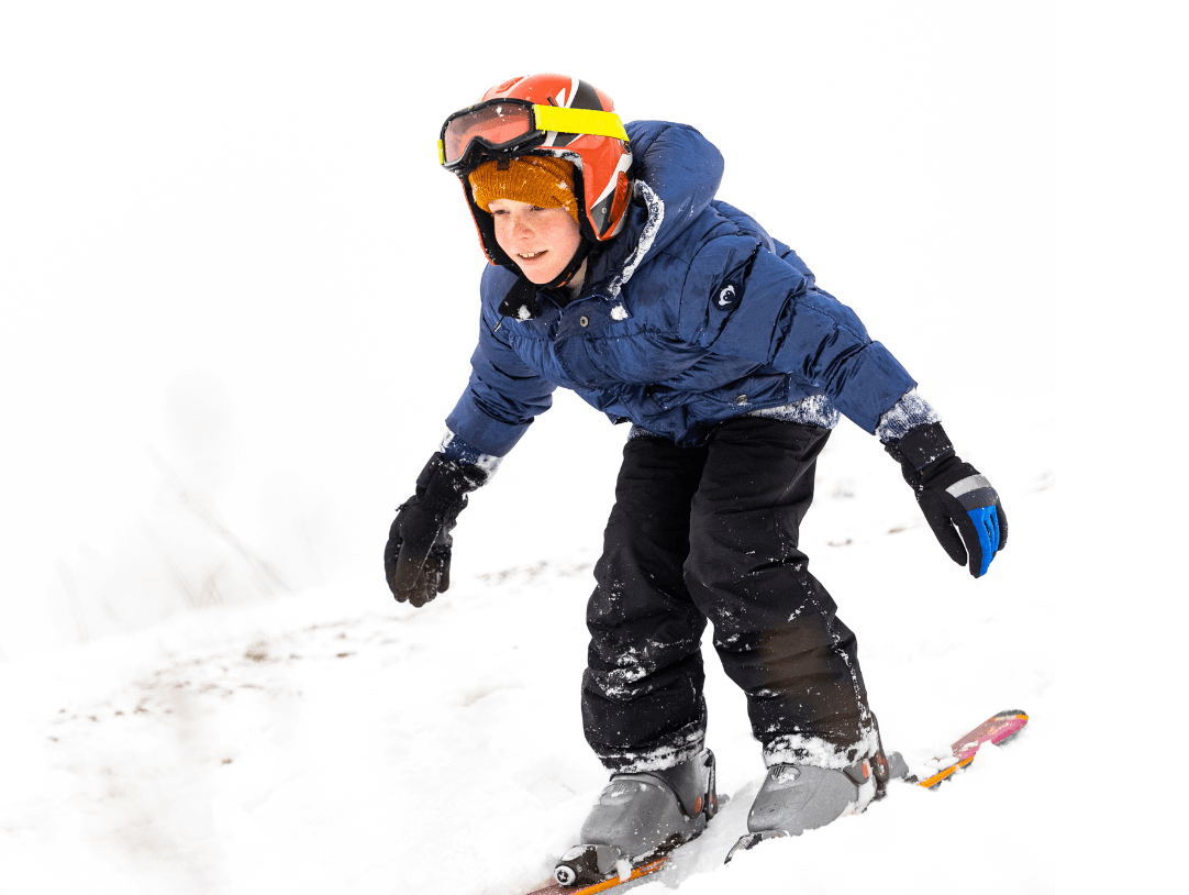 A joyful child skiing down a snowy slope, showcasing the thrill of family winter adventures.