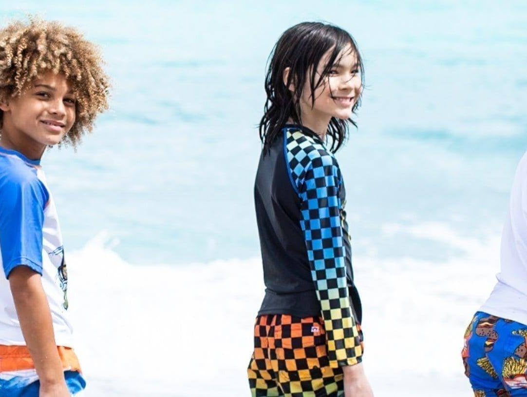 Trendy kids in colorful swimwear enjoying a sunny beach day, showcasing stylish sun protection options.