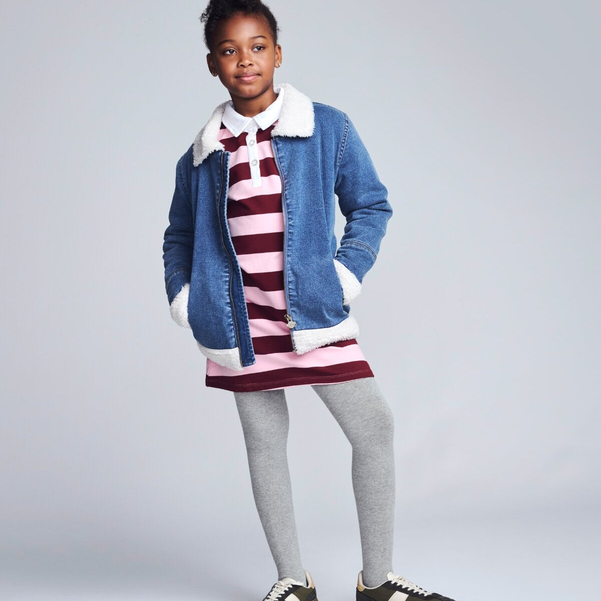 Kids’ Jackets & Coats featuring a girl smiling in a black puffer jacket with a fur-lined hood.