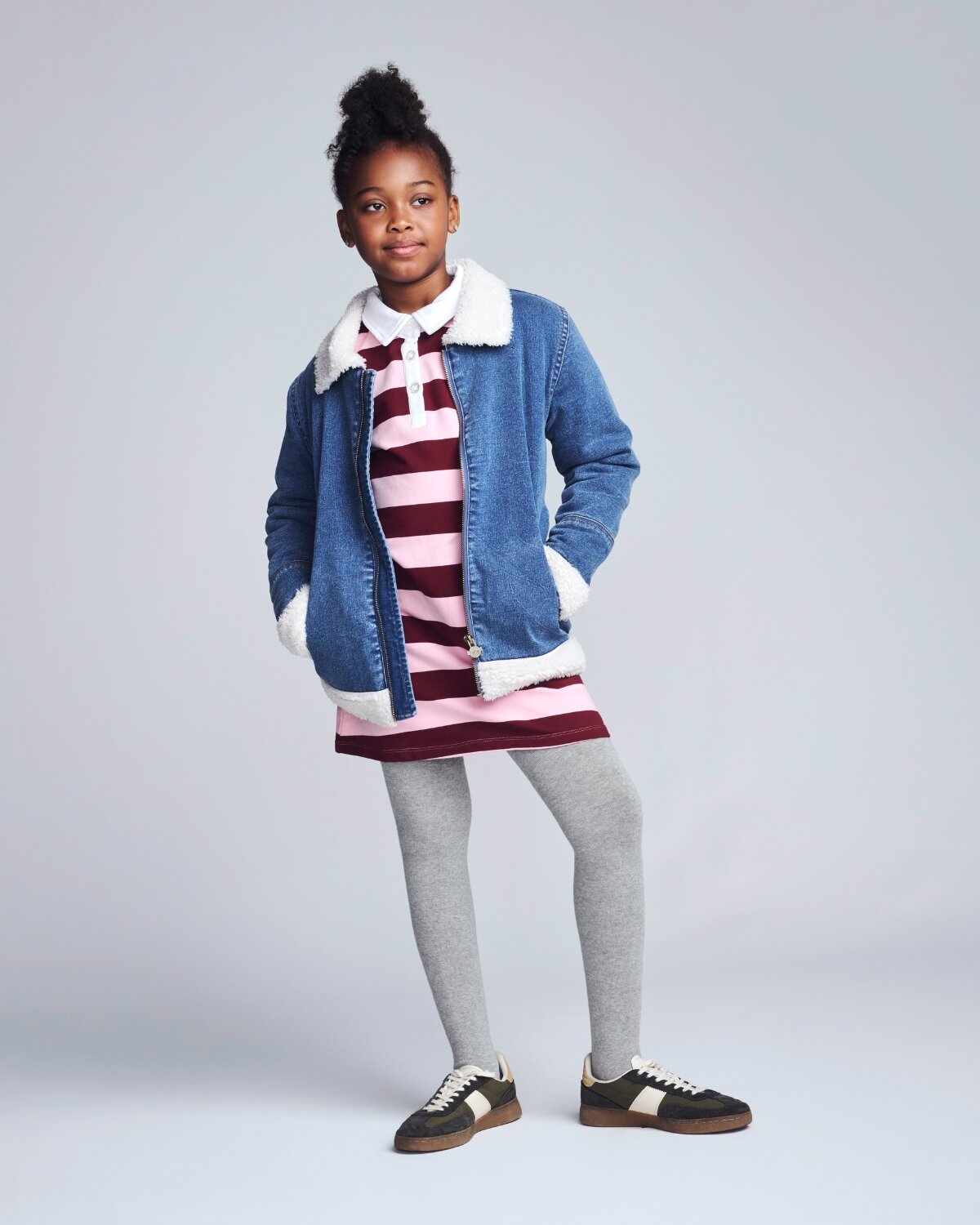 Kids’ Jackets & Coats featuring a girl smiling in a black puffer jacket with a fur-lined hood.