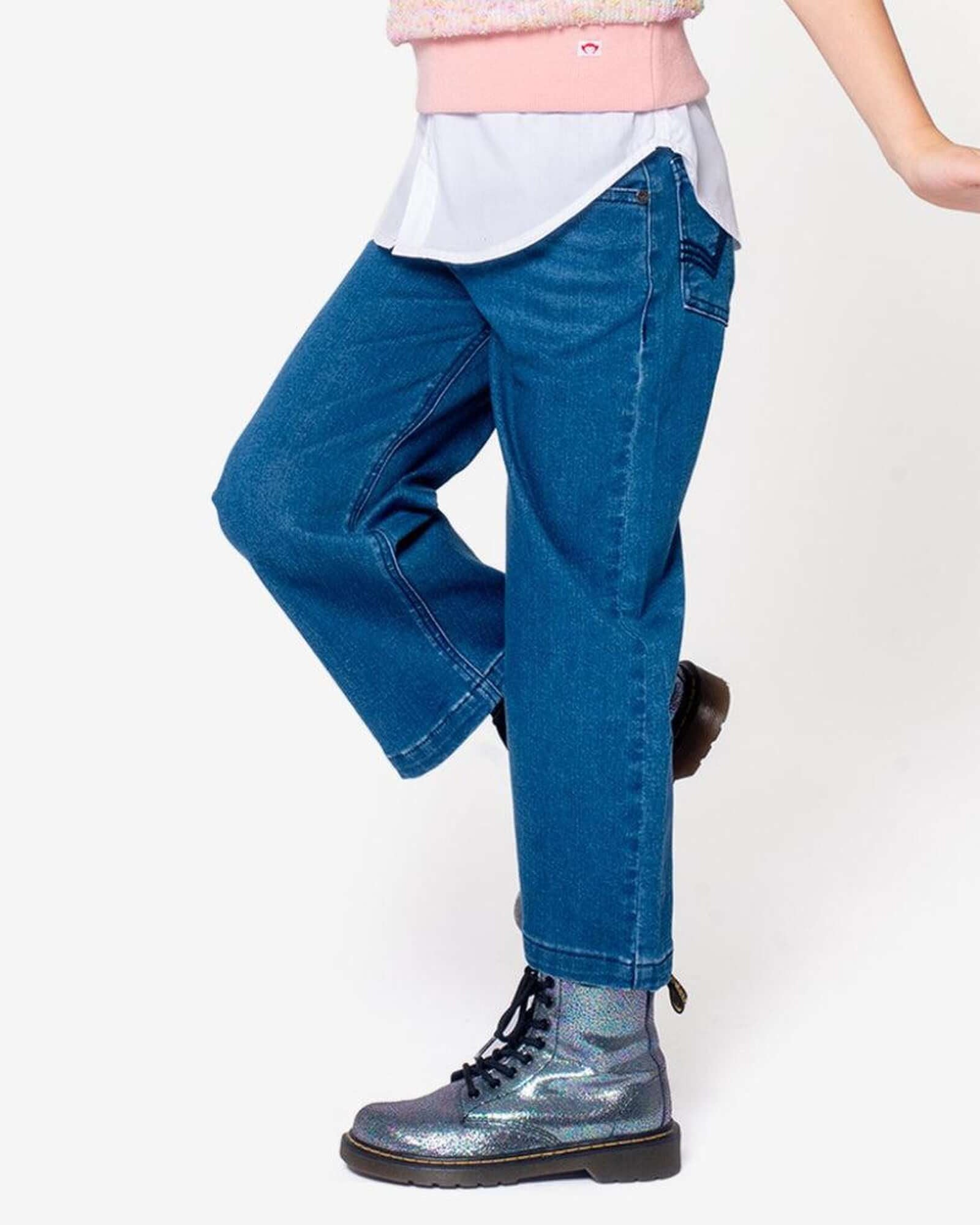 Girl wearing stylish Girls' Denim Jeans with shiny boots, showcasing playful childhood fashion.