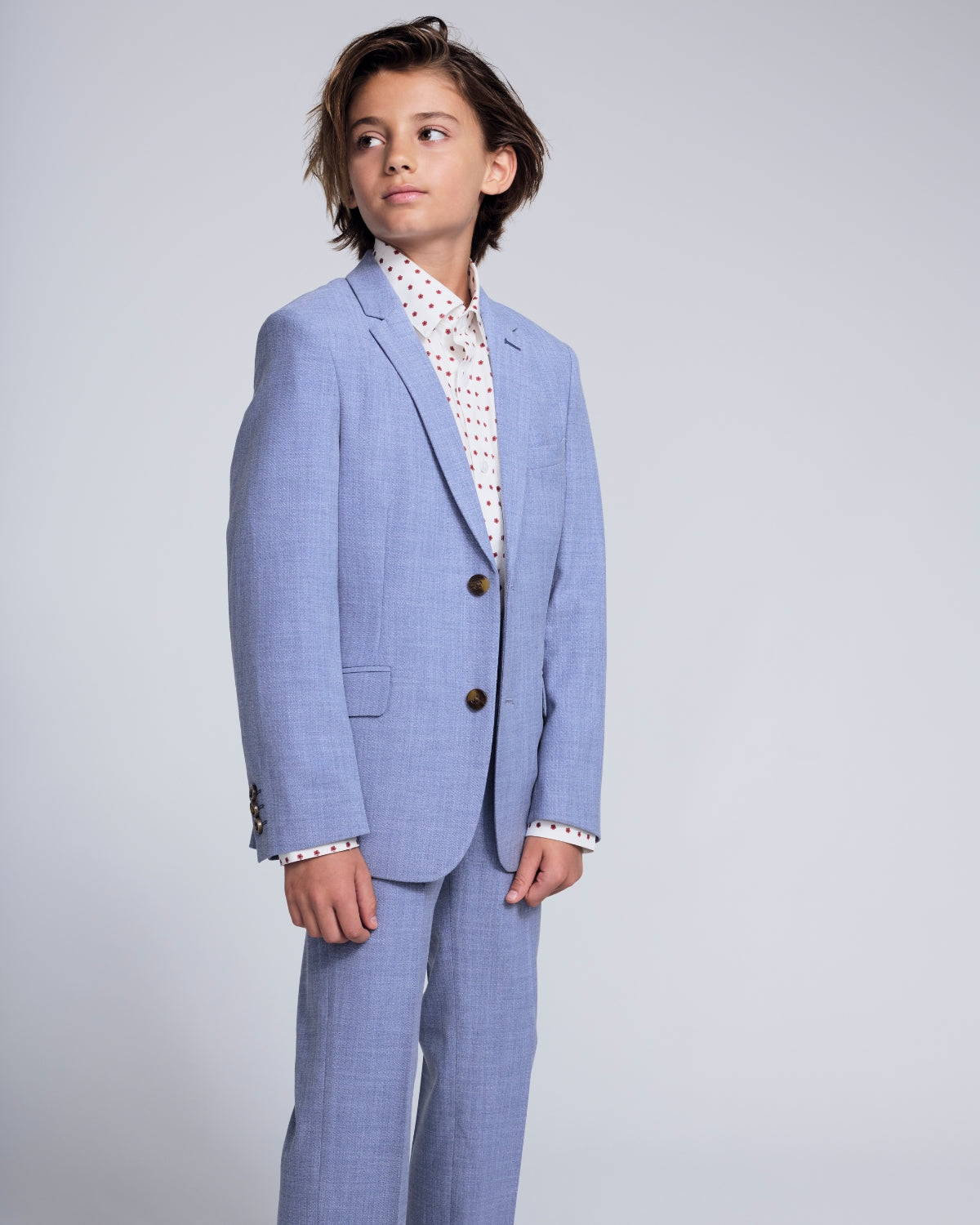 Boys' Seasonal Suits in various colors hanging on wooden hangers, perfect for formal events.