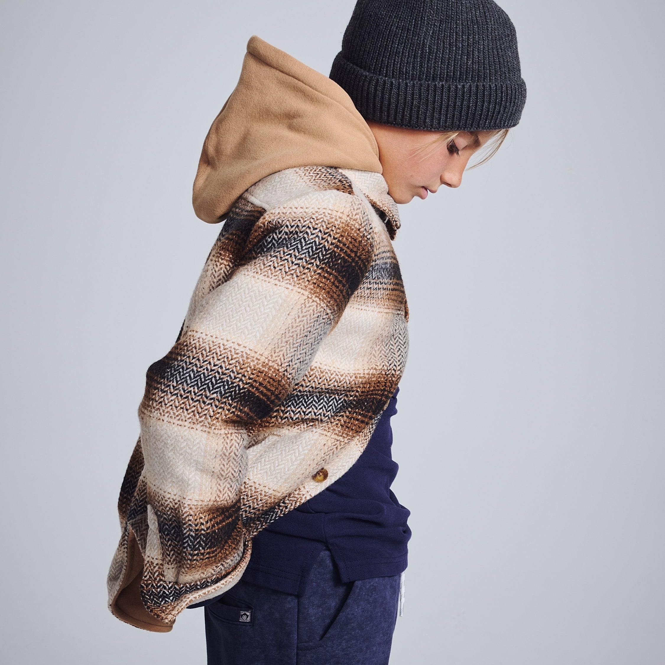 Stylish boy in a cozy flannel shirt layered with a hoodie, rocking a laid-back look for back to school adventures.