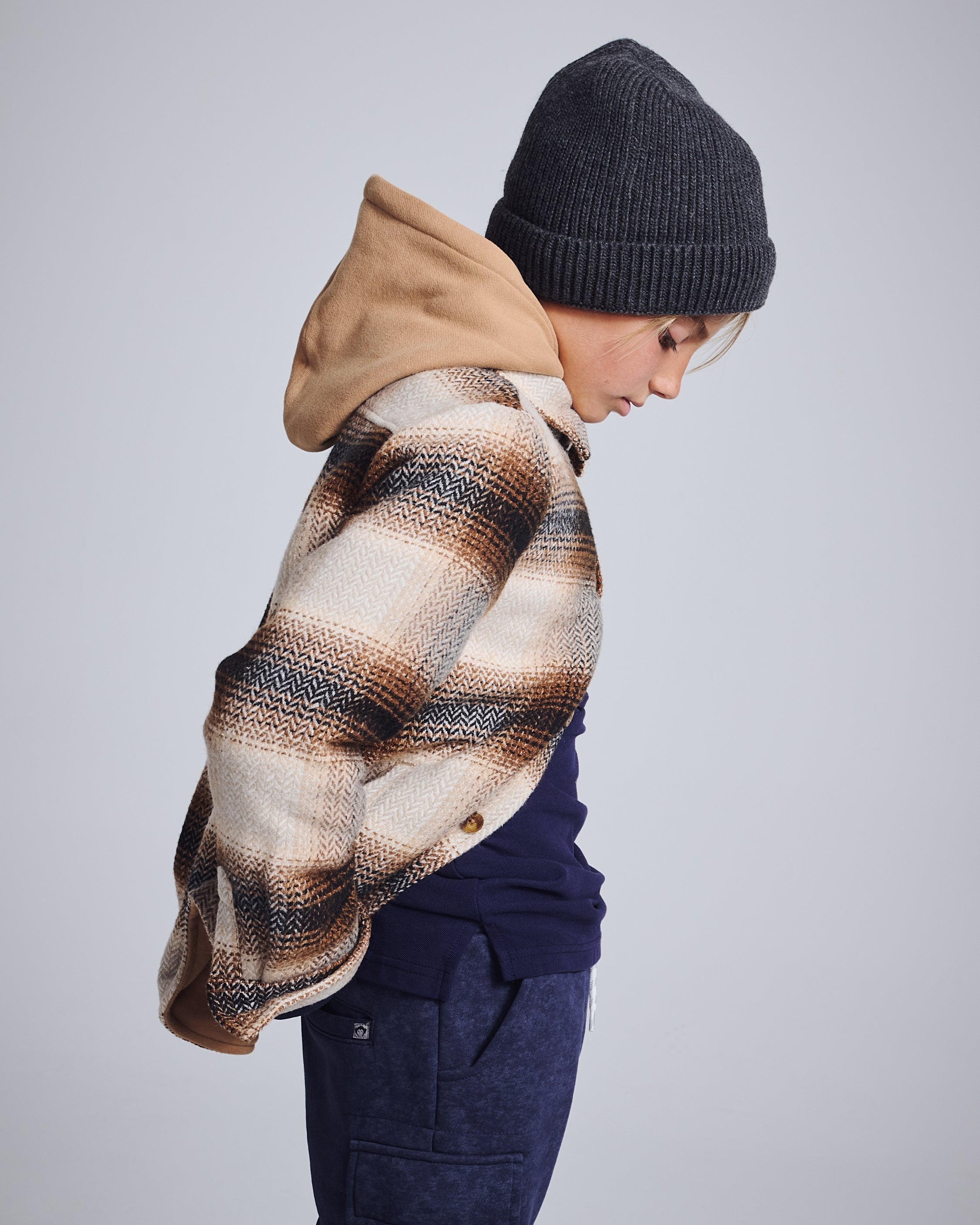 Boys' Flannel Shirts: A stylish boy wearing a flannel shirt with a hoodie and beanie, ready for fall adventures.