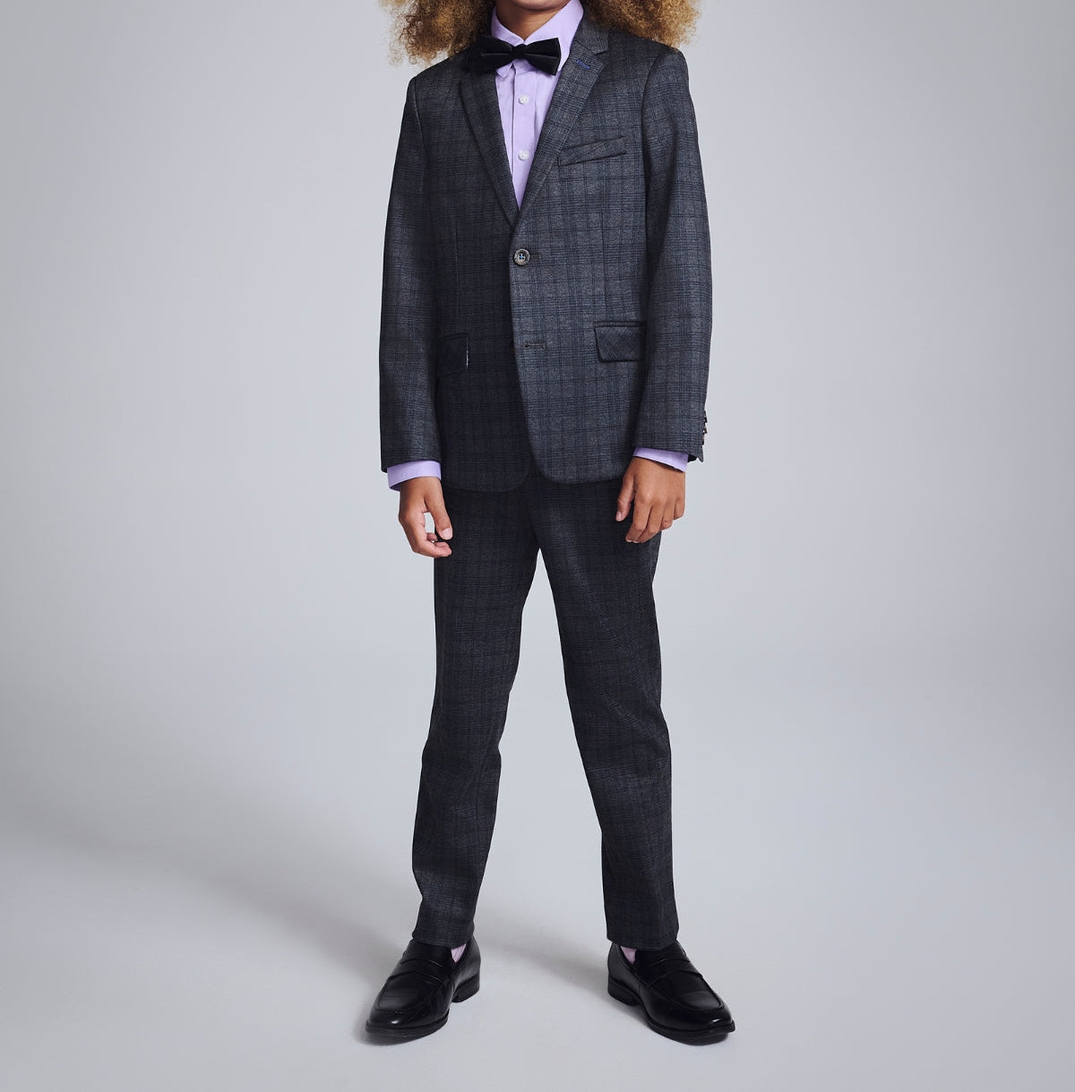 Two stylish boys in sleek suit sets share a joyful high five, showcasing modern boys' clothing for every special occasion.
