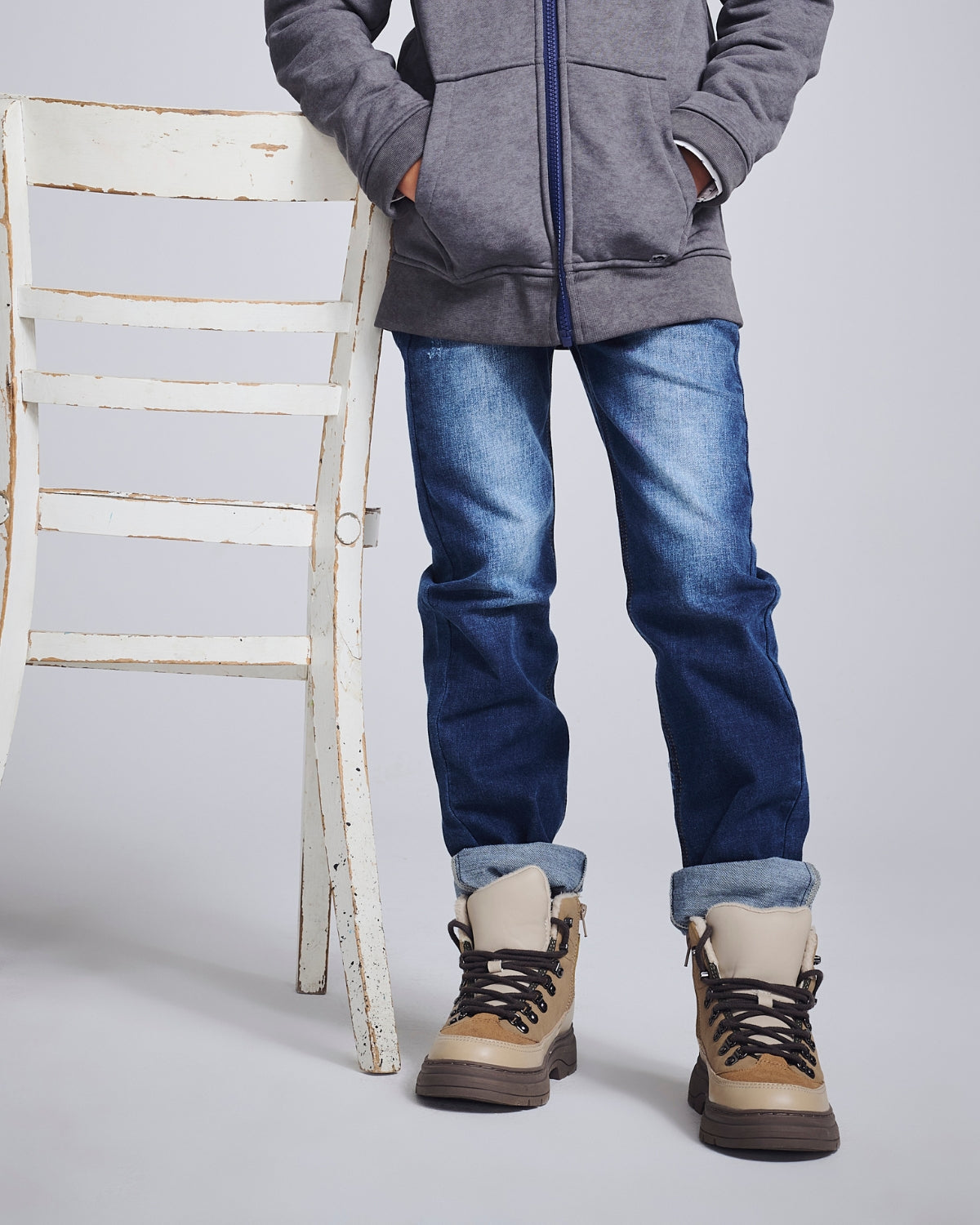 Boys' Denim Jeans worn with a gray hoodie and tan boots next to a rustic white chair.