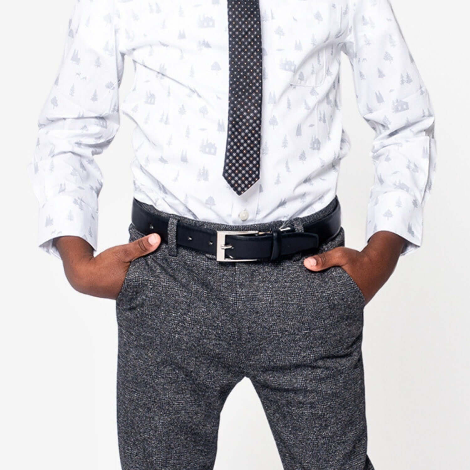 Stylish boy wearing a patterned shirt and tie, showcasing a sleek black belt with trousers for a dapper look.