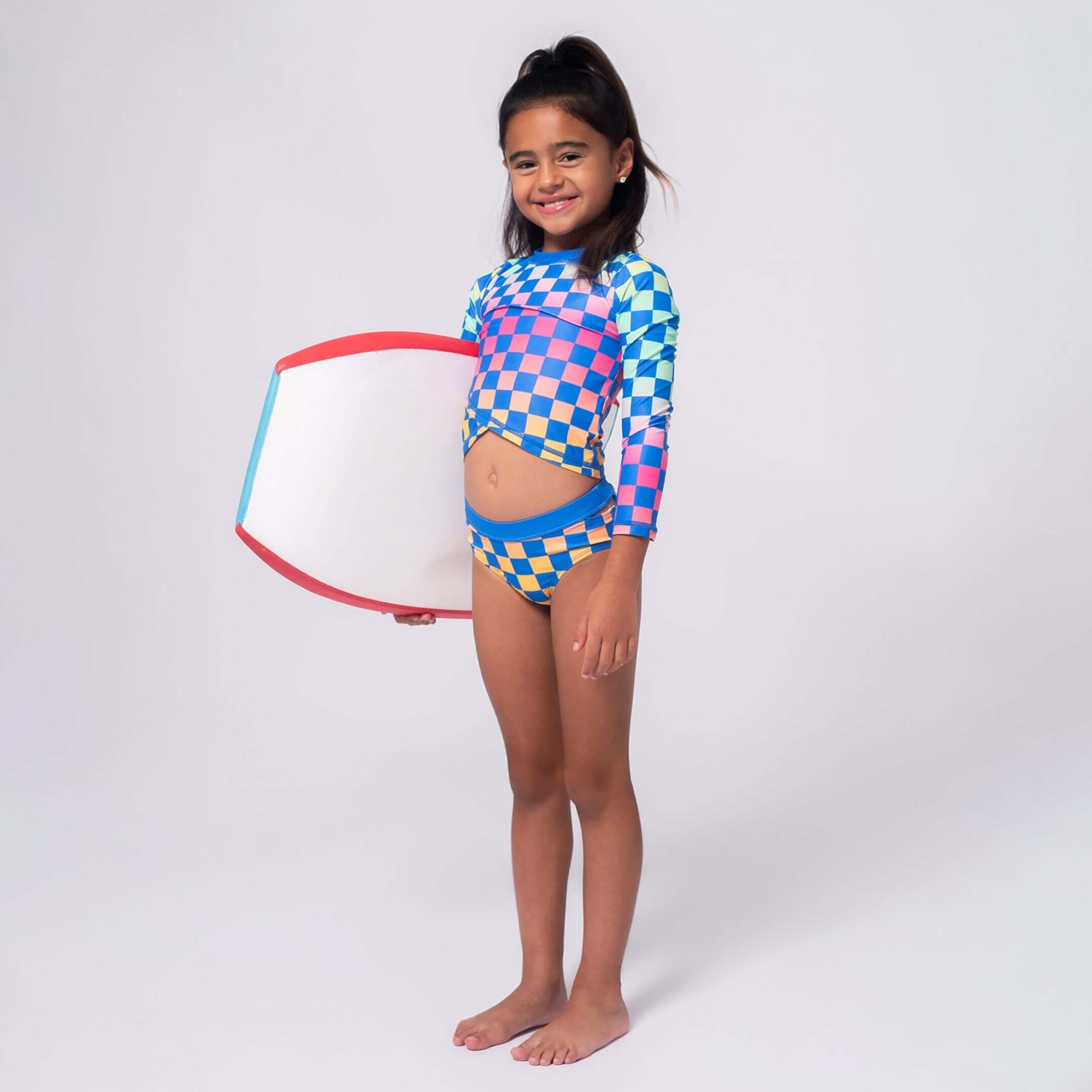 Fashion-forward girl in a colorful rash guard and swim bottom, ready for sun-soaked fun and beach adventures!