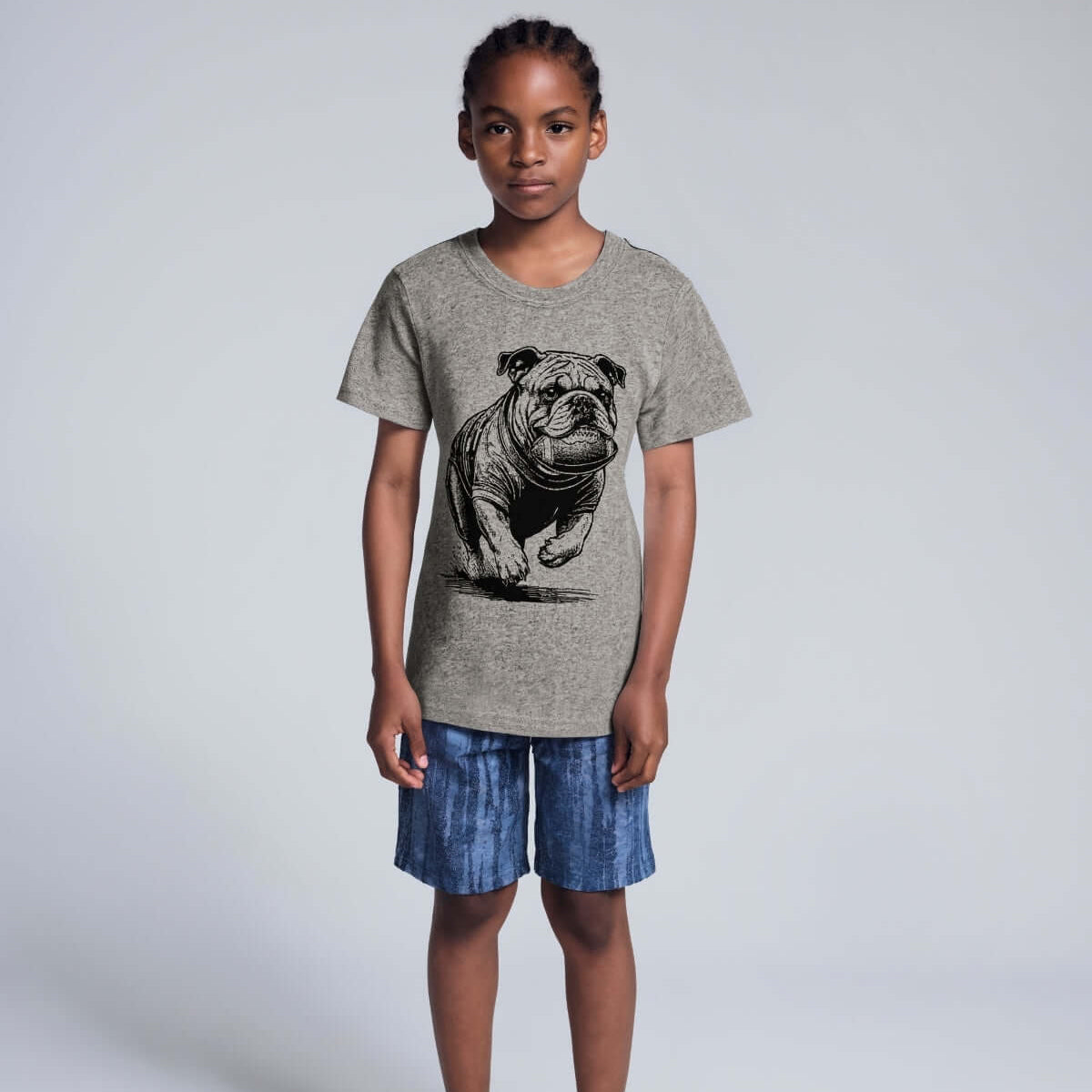 Child wearing a gray t-shirt with a dog graphic and blue shorts on a white background