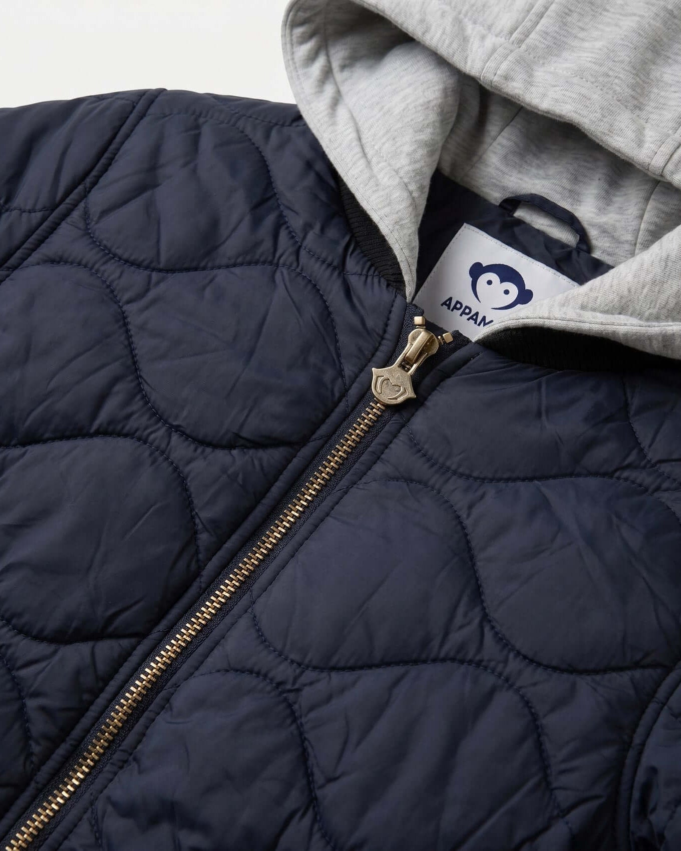 Navy quilted jacket with gold zipper and gray hood, featuring a brand label.