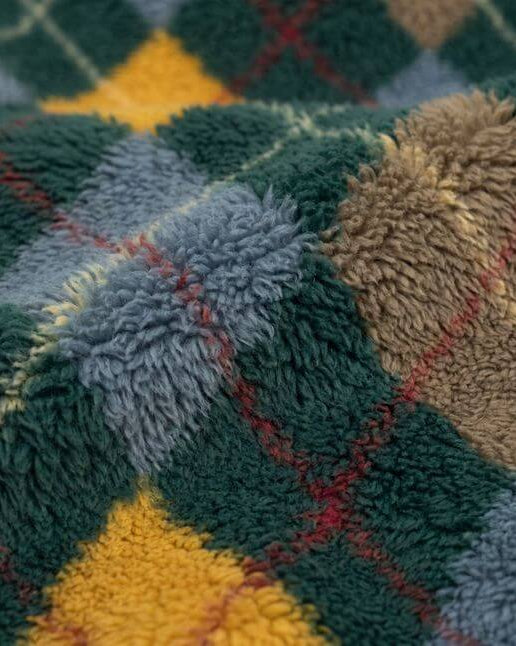 Close-up of a textured, multicolored plaid fabric with green, yellow, red, and blue patterns.
