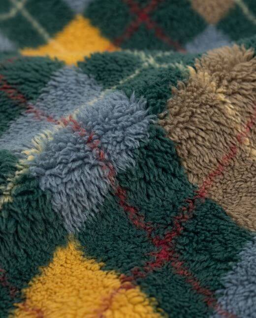 Close-up of a textured, multicolored plaid fabric with green, yellow, red, and blue patterns.