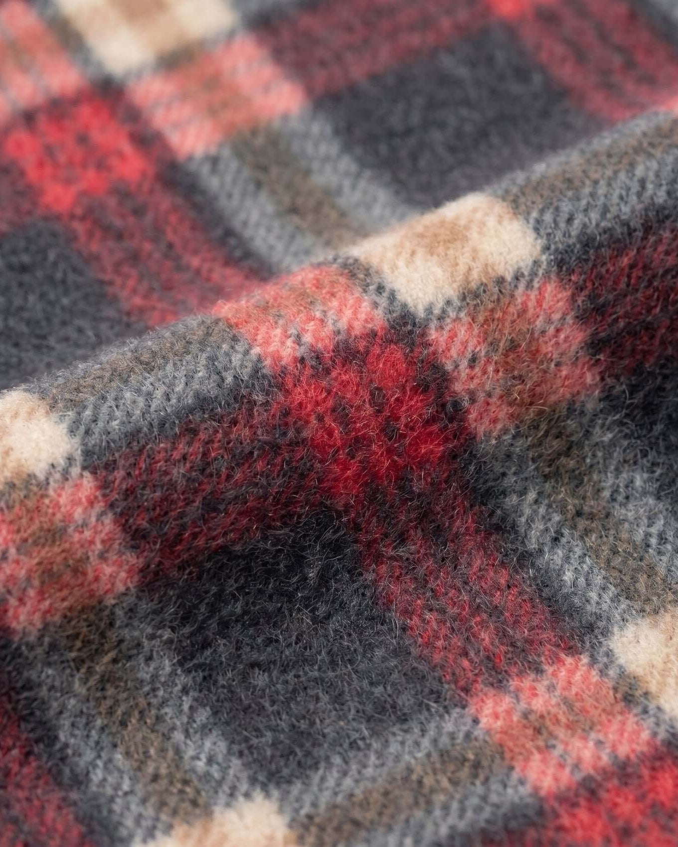 Close-up of a plaid fabric with red, black, and beige colors.