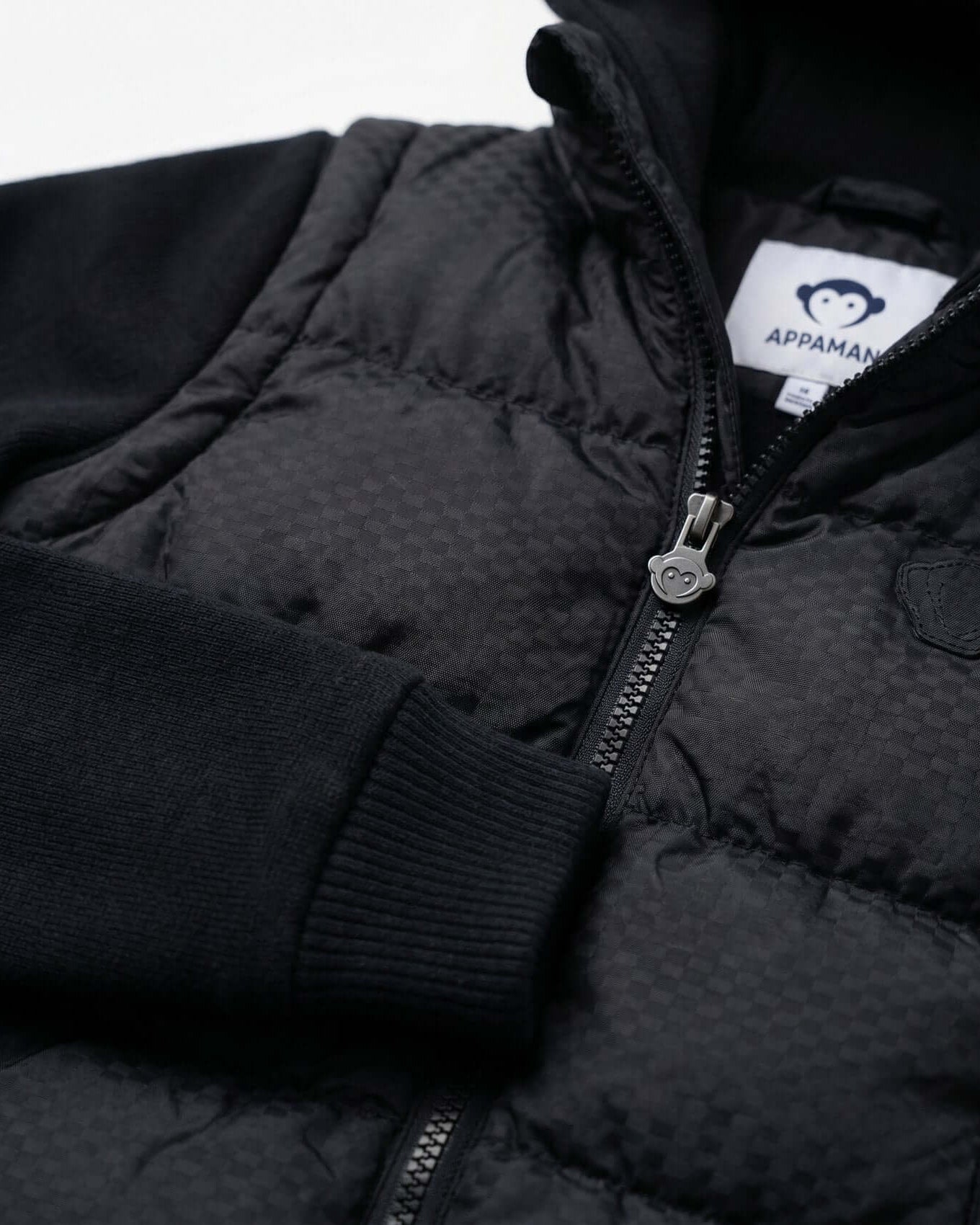 Close-up of a black puffer jacket with a visible brand label on a white background
