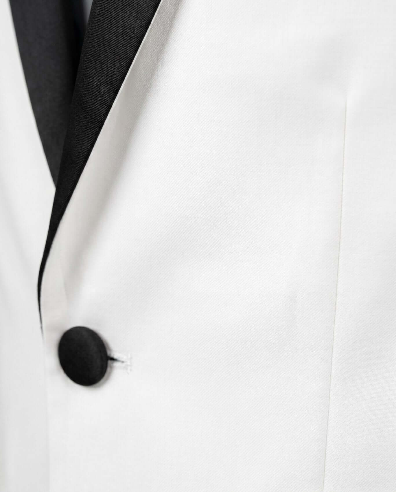 Close-up of a white suit jacket with a black lapel and button.
