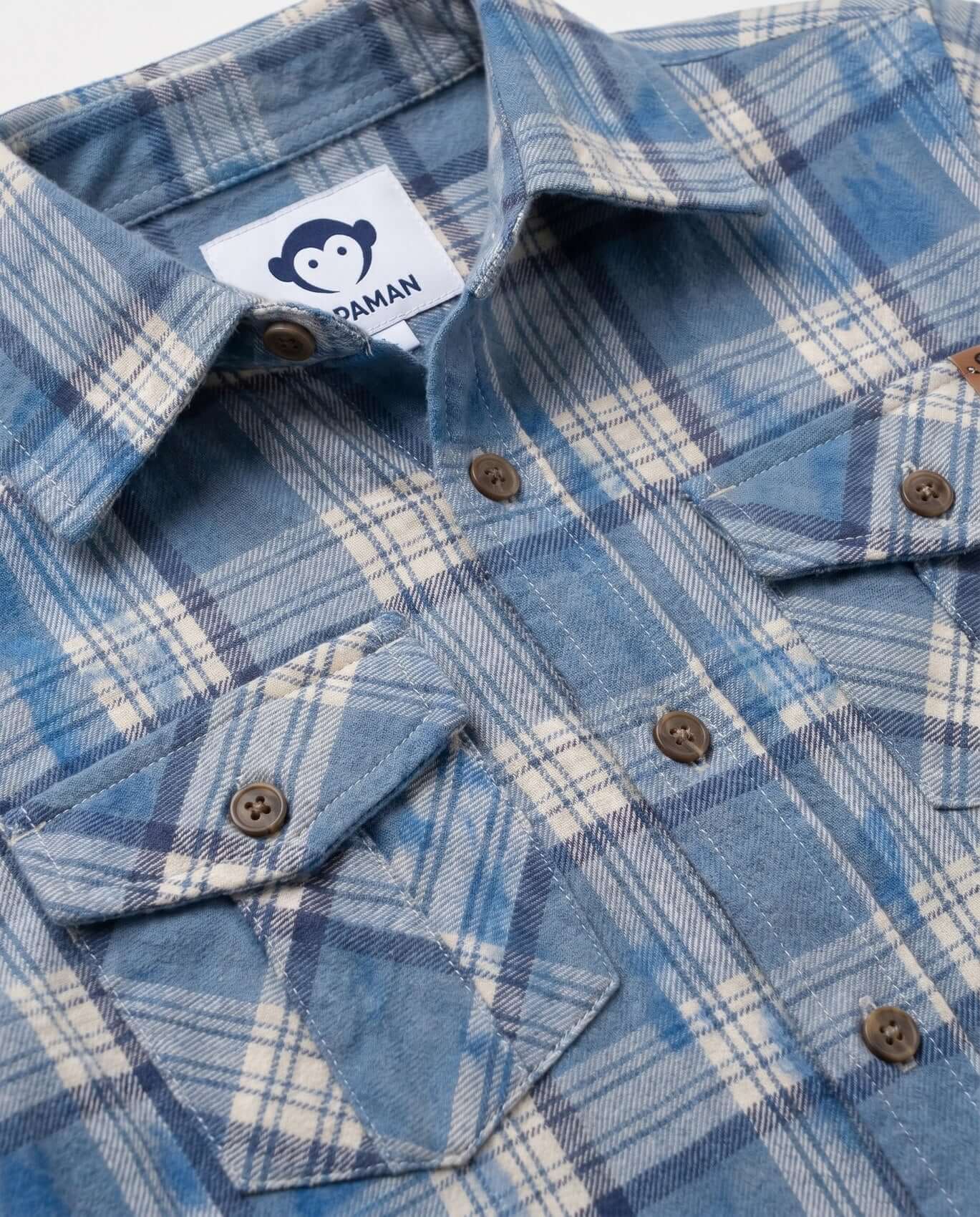 Close-up of a blue plaid shirt with a brand label on a white background