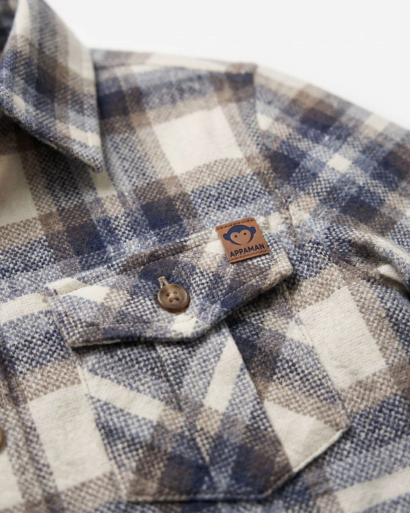 Close-up of a plaid shirt with a brand label on a white background