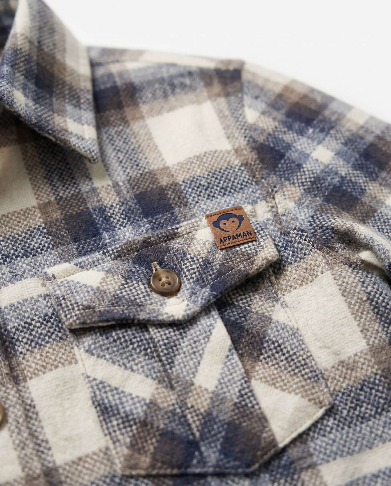 Close-up of a plaid shirt with a brand label on a white background