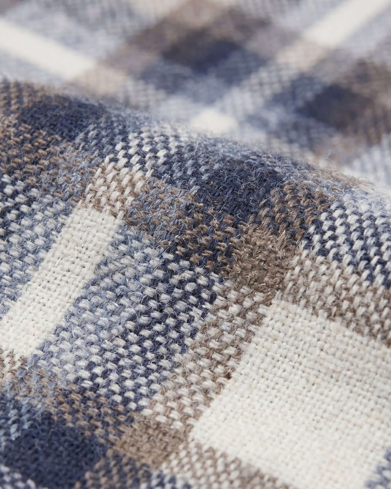 Close-up of a fabric with a plaid pattern in blue, brown, and beige.