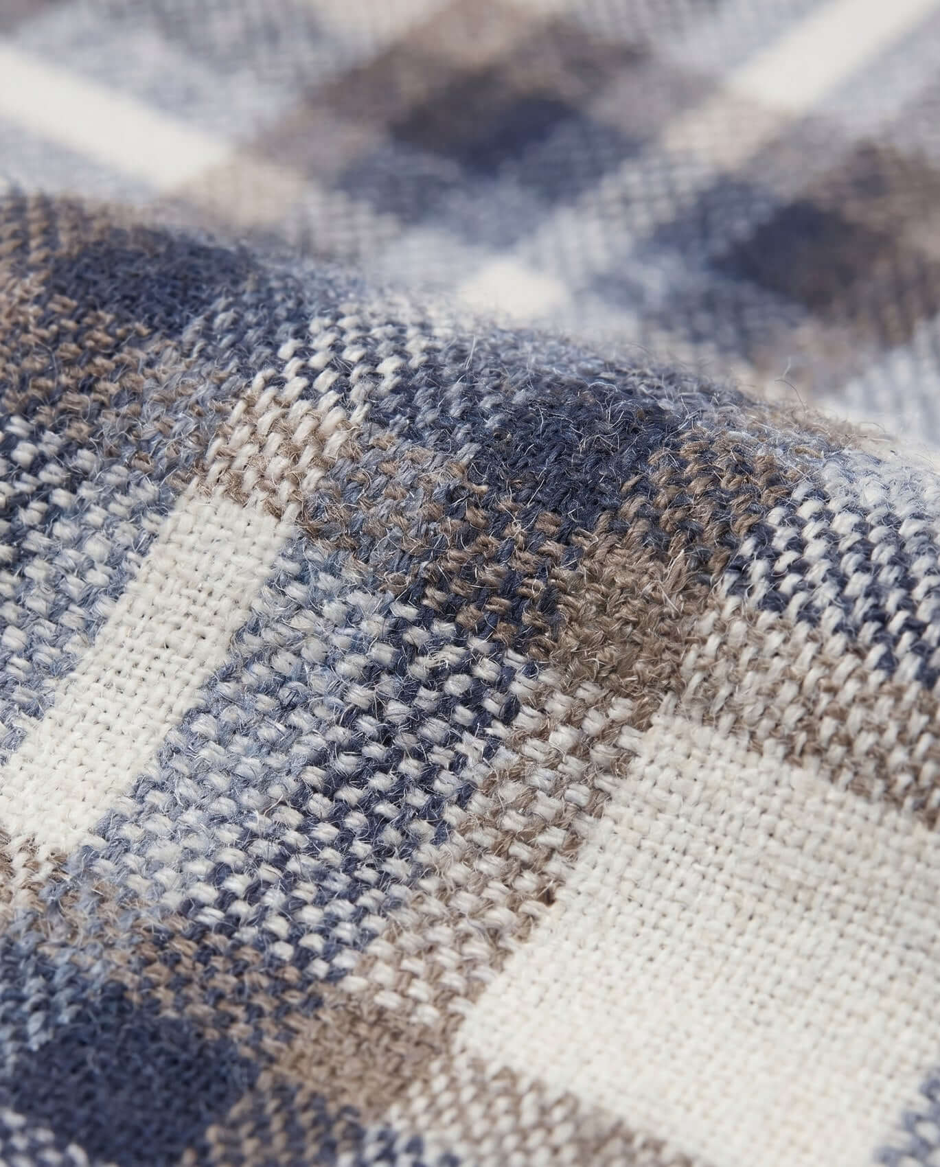Close-up of a fabric with a plaid pattern in blue, brown, and beige.