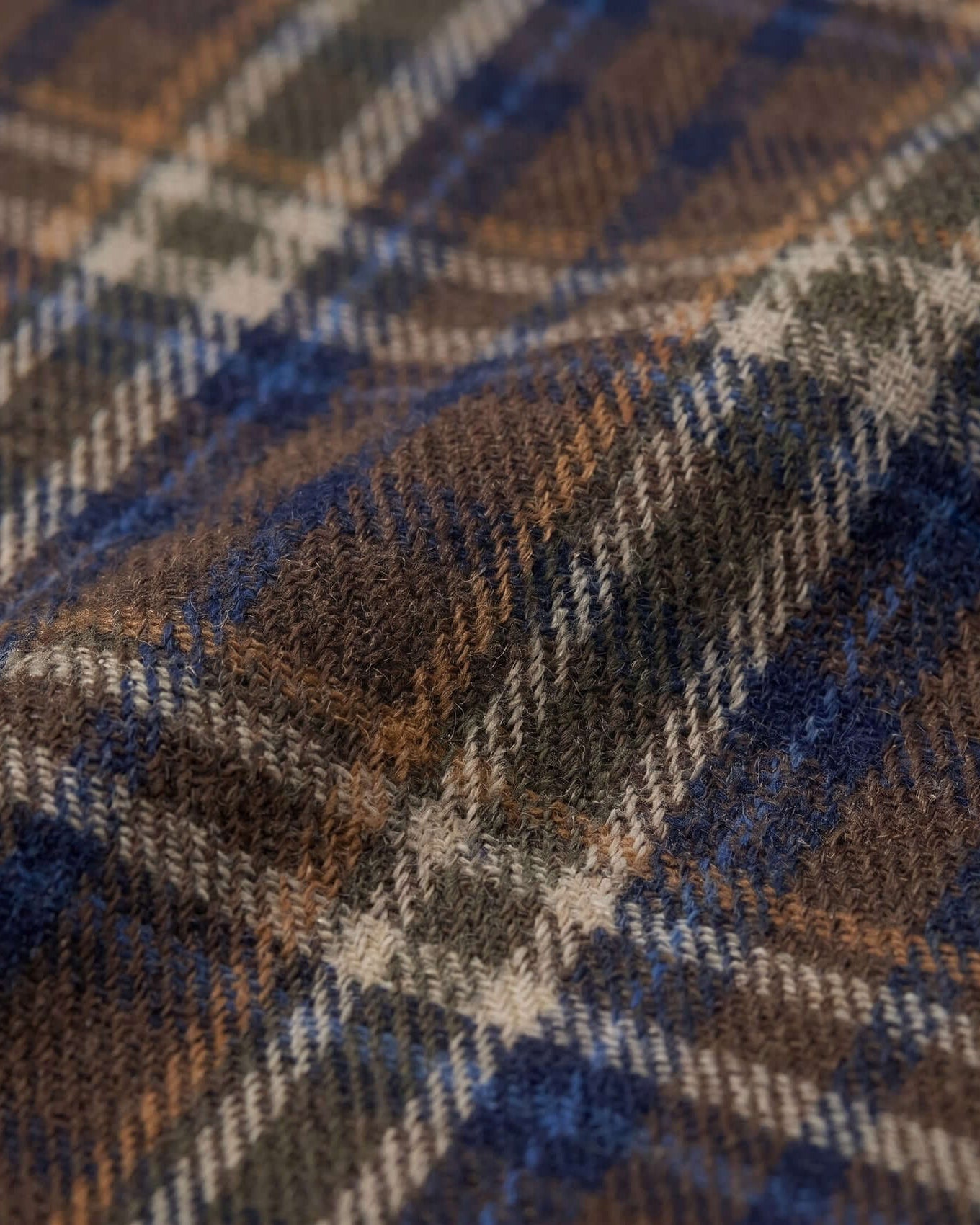 Close-up of a plaid fabric with brown, blue, and beige colors.