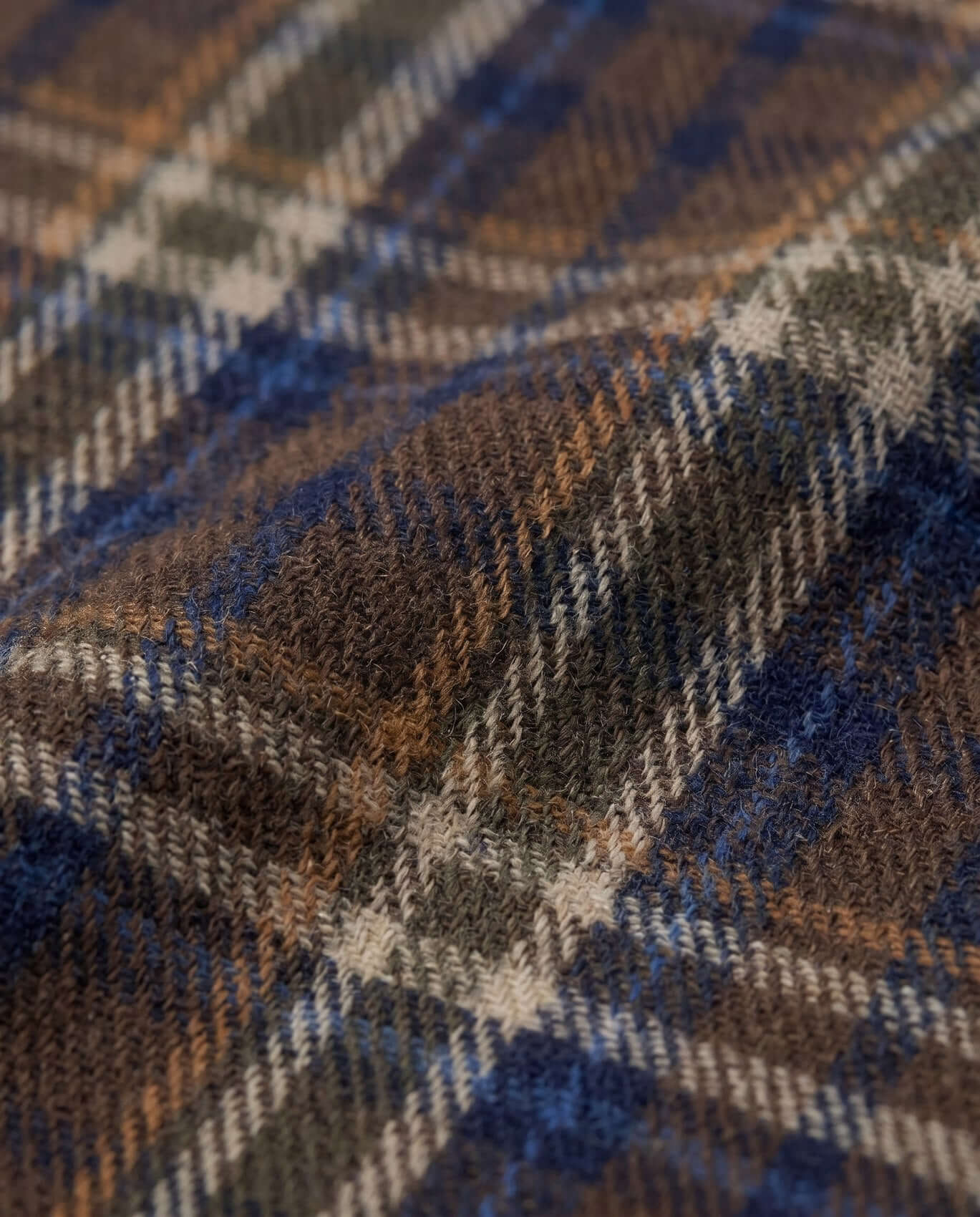 Close-up of a plaid fabric with brown, blue, and beige colors.