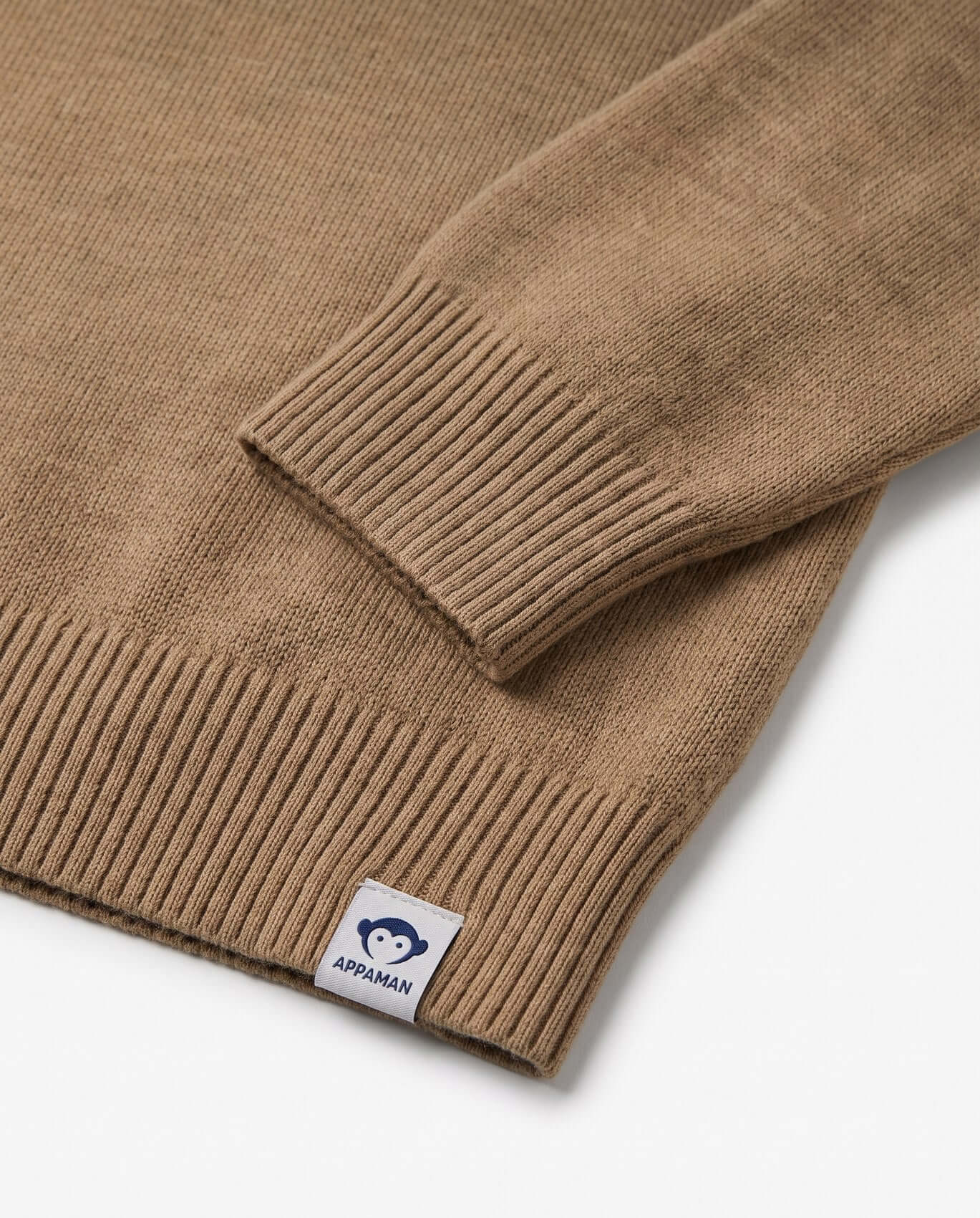 Close-up of a brown sweater with a visible brand label on a white background
