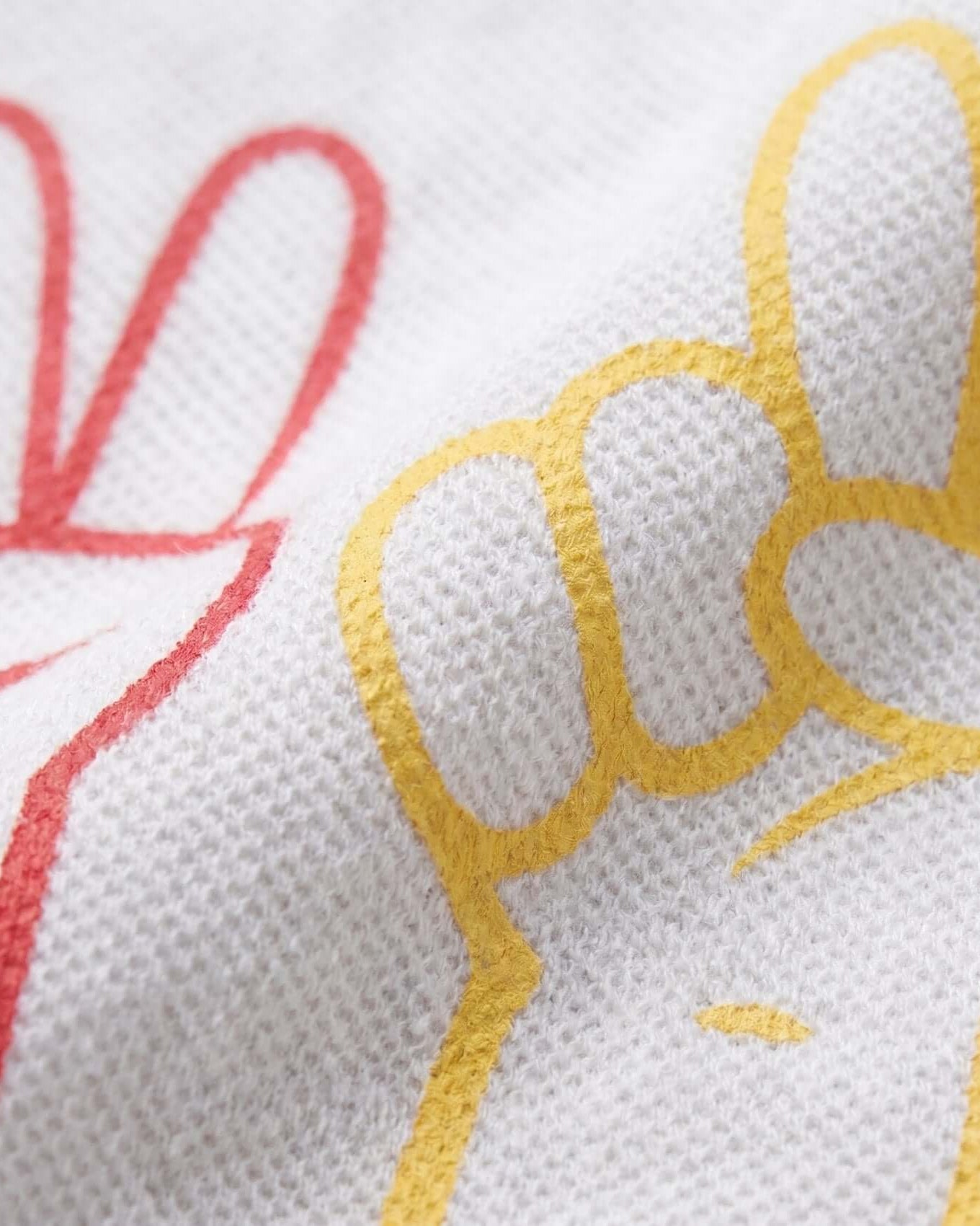 Close-up of embroidered text on a white fabric with red and yellow thread.