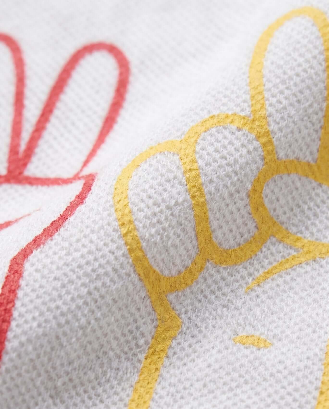 Close-up of embroidered text on a white fabric with red and yellow thread.